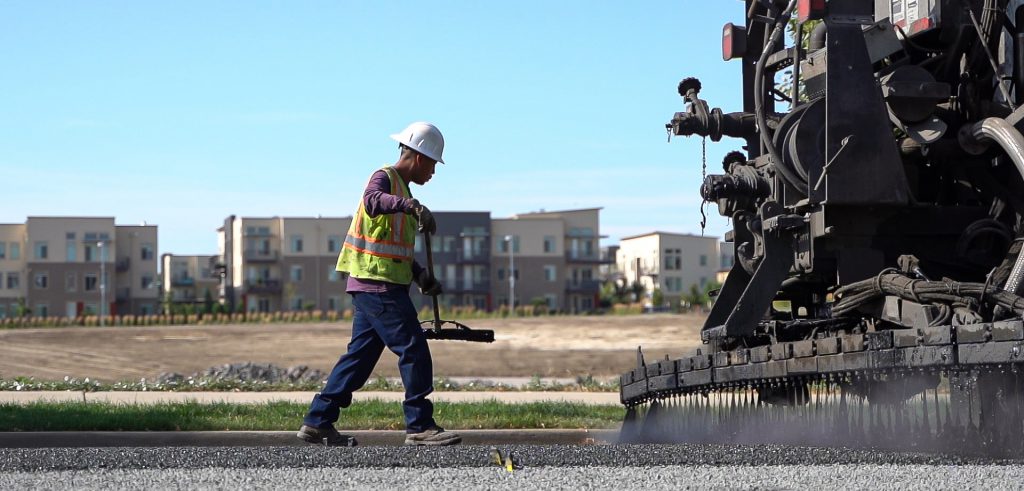 Asphalt worker with paving machine on road