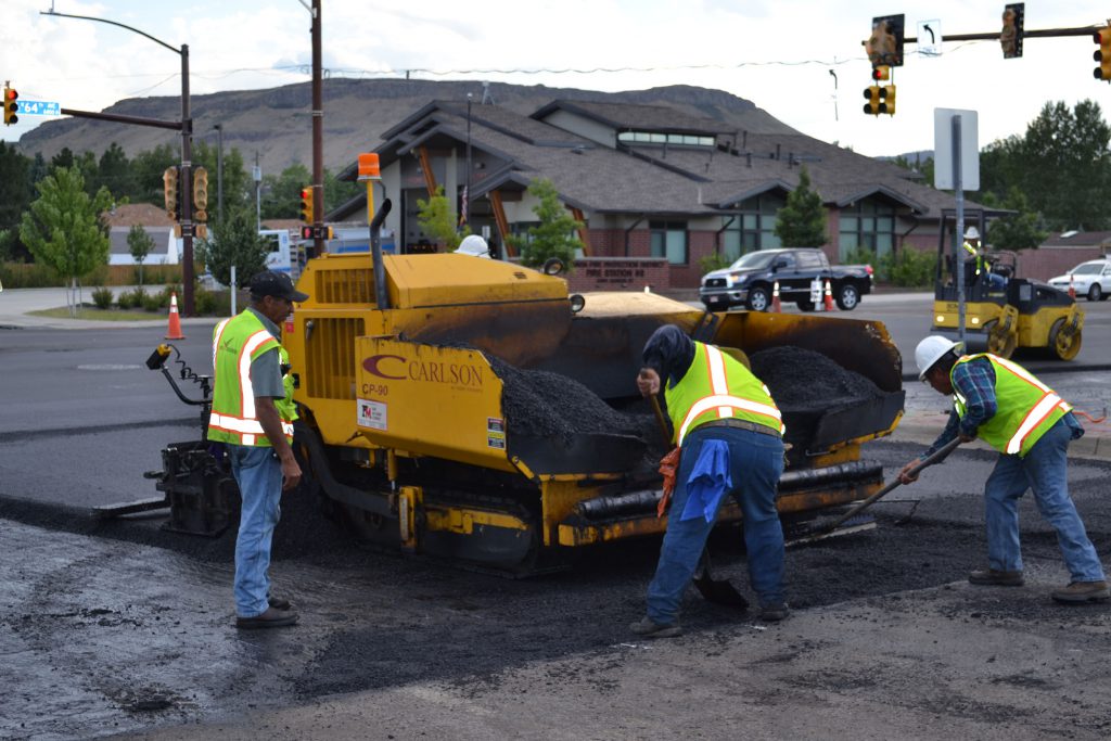 asphalt pavement workers using machinery on road
